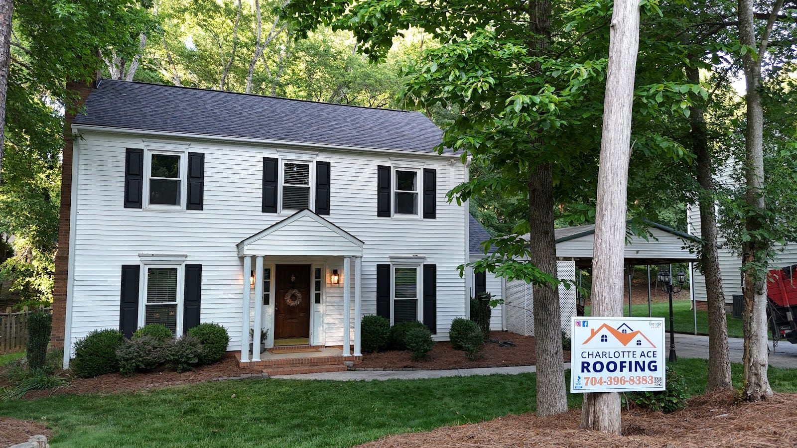 White two-story home with a new roof and a Charlotte Ace Roofing sign