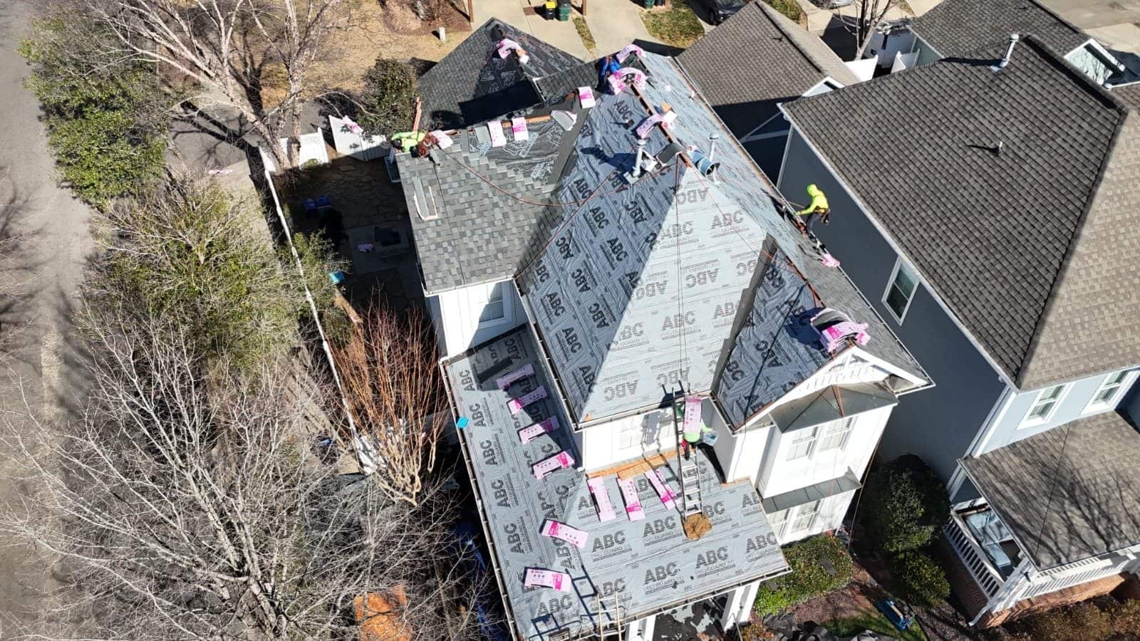 Crew installing synthetic underlayment on a two-story Charlotte home