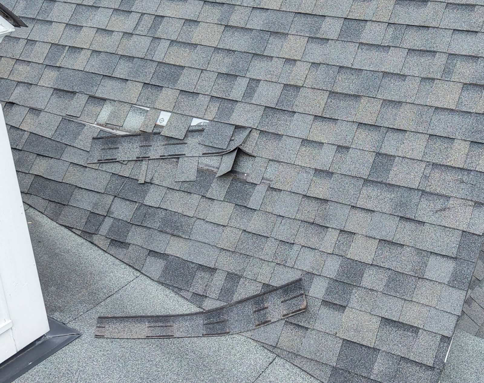 Storm-damaged shingles blown off a roof before repair in Charlotte, NC
