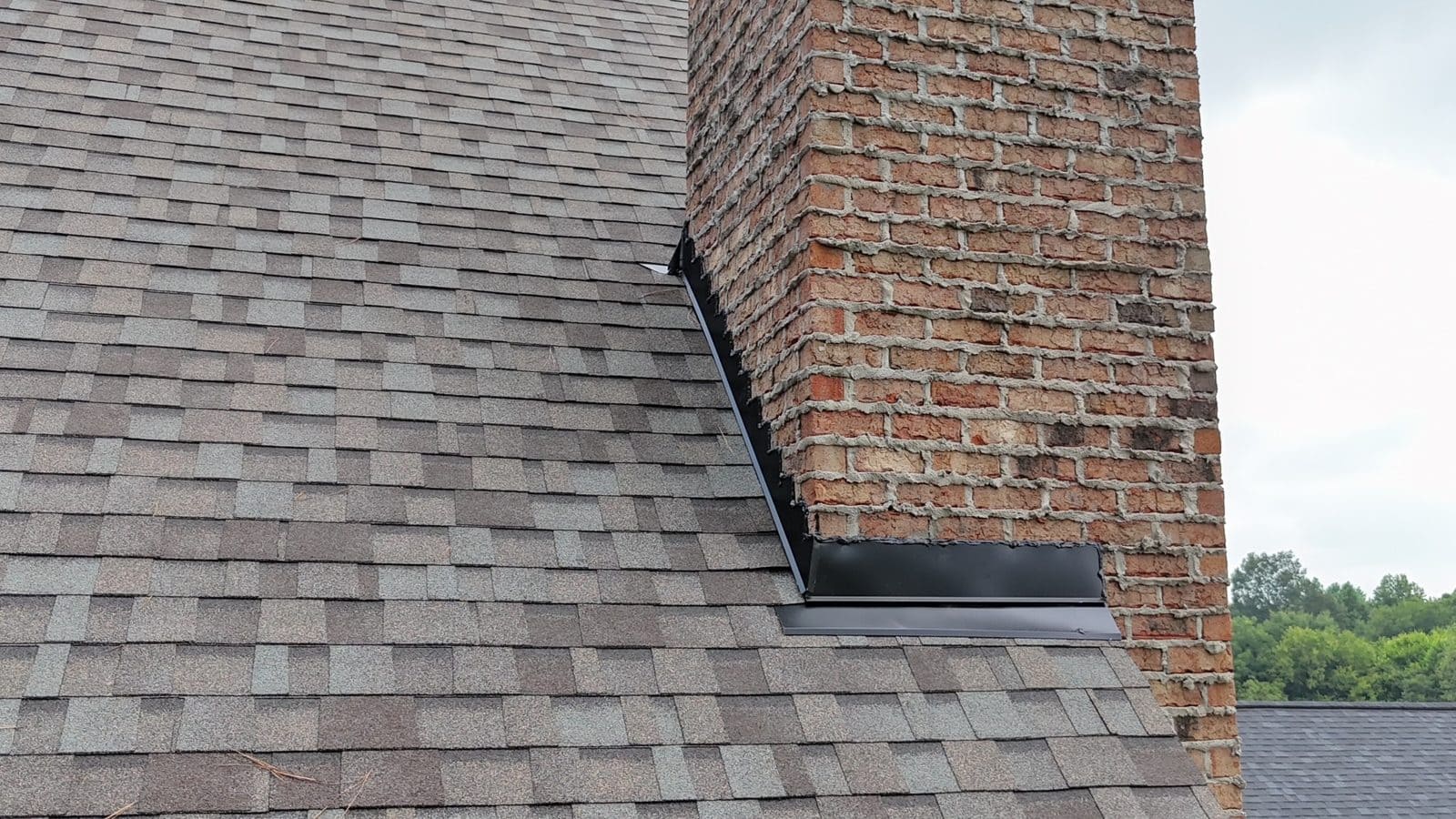 New step and counter flashing around a brick chimney with new shingles in Charlotte, NC