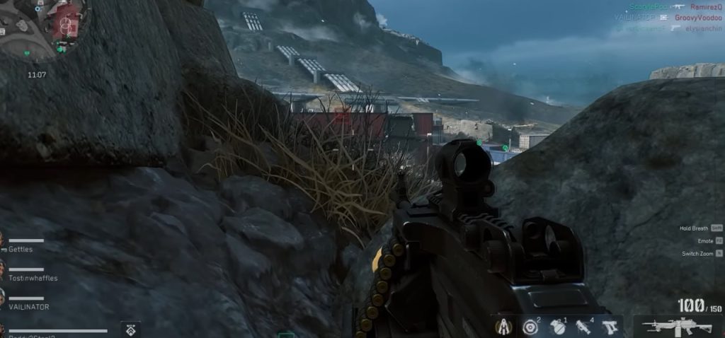 Delta Force first person view from behind rocks overlooking a military outpost in a mountainous battlefield area