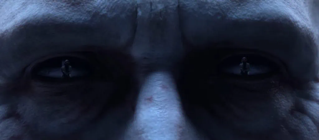 Extreme close-up of a pale face and dark eyes in Diablo 4 with reflected figures visible in both pupils
