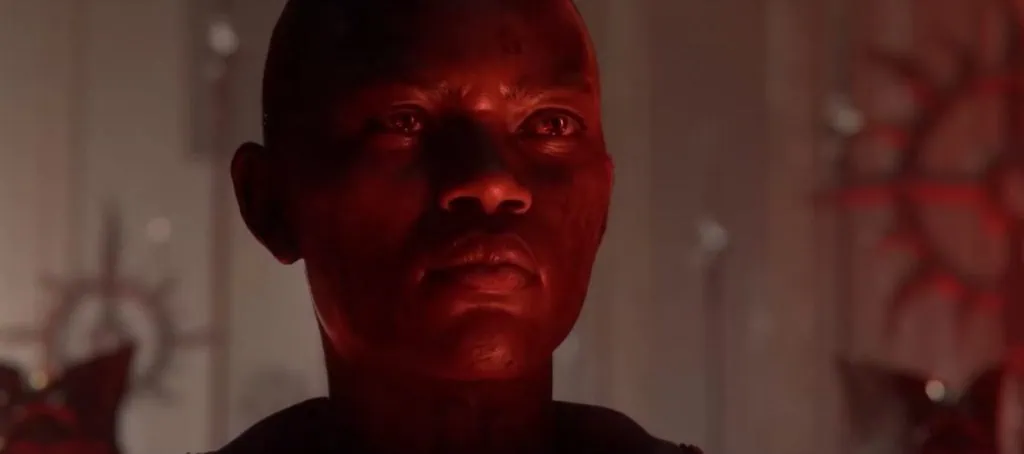 Red-lit close-up of a Diablo 4 character in a dark cinematic scene with a serious expression
