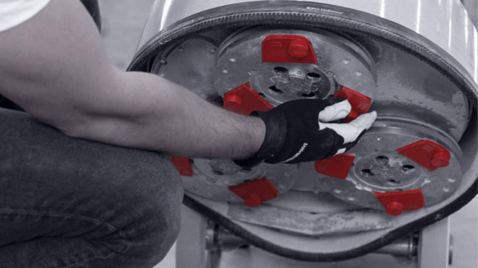 Gloved hand adjusting red diamond grinder pads