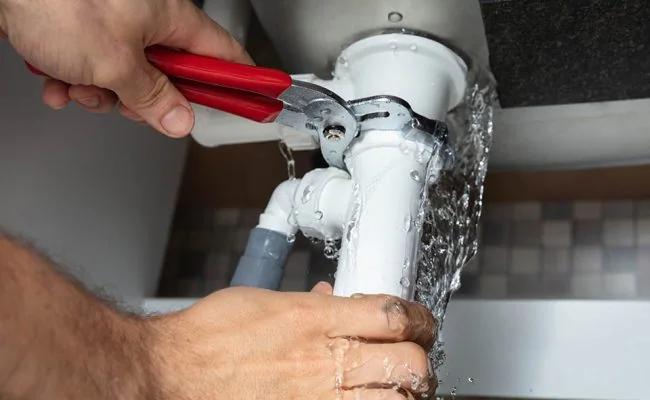 Plumber Fixing Sink Pipe With Adjustable Wrench