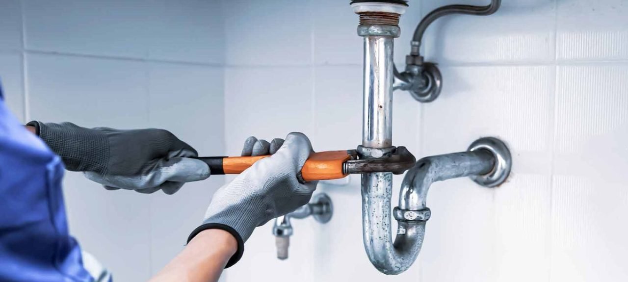 An HVAC Technician repairing pipes of a sink.