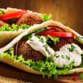 Falafel and fresh vegetables in pita bread on wooden table