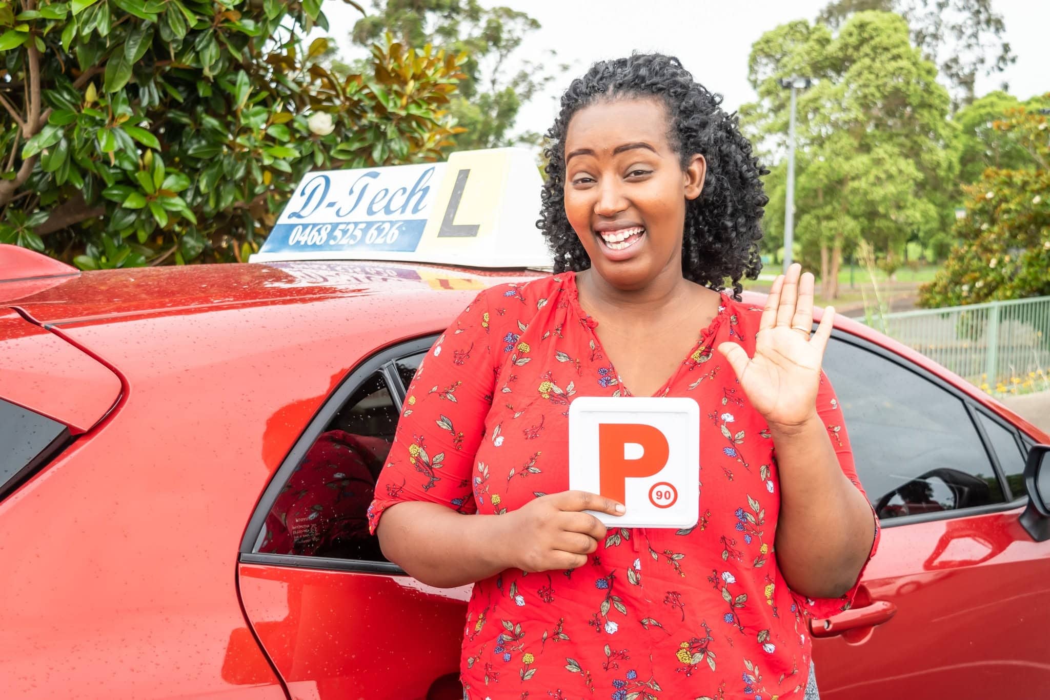 D-Tech Driver Training student smiling and holding her new NSW P-plates next to the D-Tech driving school car after passing her practical test near Ropes Crossing.