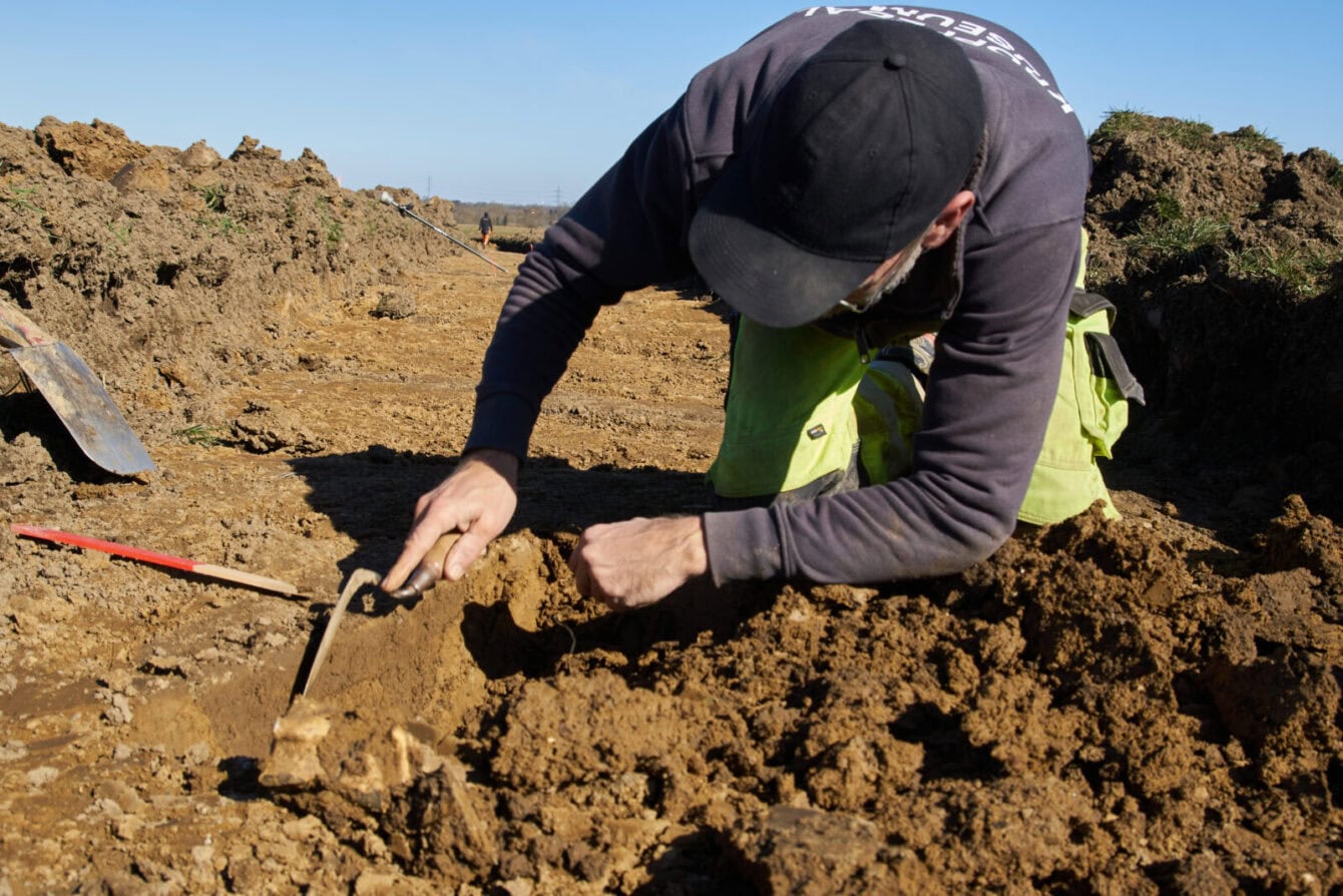 Kroppedal Museum foretager Arkæologiske undersøgelser på Hedeland forud for Spejdernes Lejr 2026. Når man har gravet med spaden og stødt på noget, må man i gang med mindre redskaber, også selv om det som regel viser sig at være en sten. Bo Jensen fra museet er i gang med et sort område ca. 1,5 meter, hvor nogen engang har gravet en hul. 
Foto: Jakob Skipper.