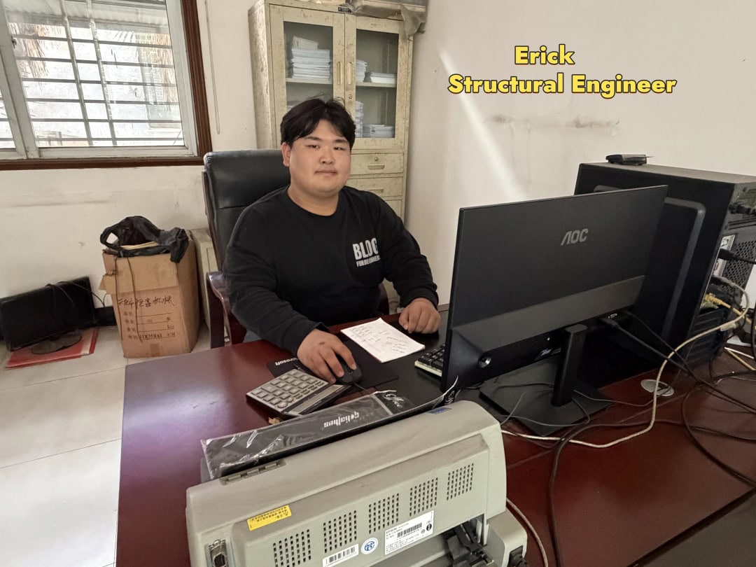 Person seated at a desk with a computer and documents in the factory office