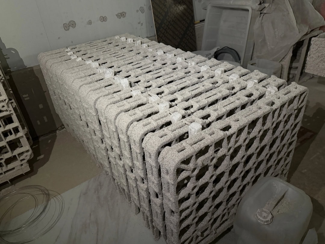 Rectangular open-grid furnace components stacked upright in the workshop