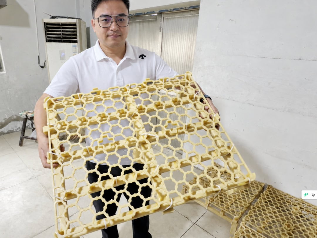 Jonny holding an open-grid wax pattern for a furnace tray in the ECOOSUN workshop