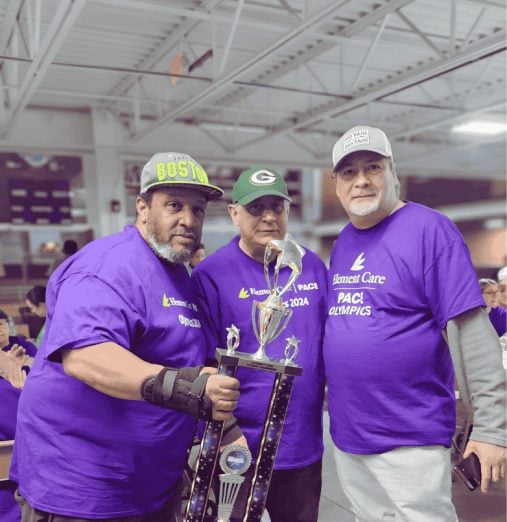 Three Element Care PACE participants celebrating with trophy at adult day health center
