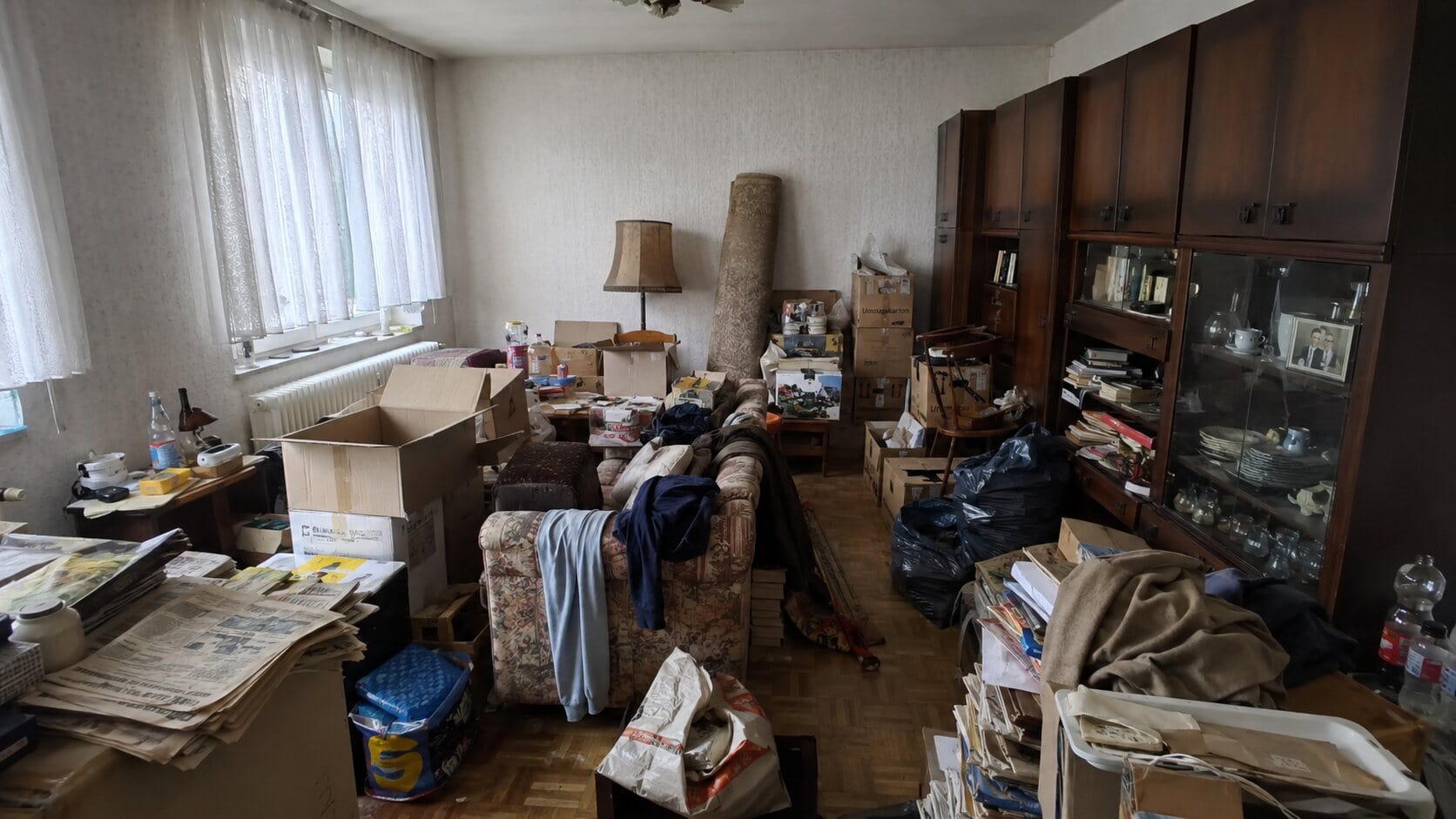 Vollgestellte verwahrloste Wohnung mit Möbeln und Hausrat vor der Entrümpelung (KI-generiertes Symbolbild)