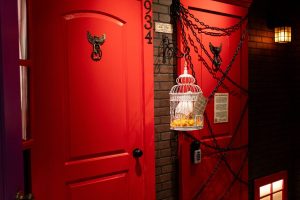 School Of Magic Escape Room with two red doors and one door covered in chains and cage in a owl hanging