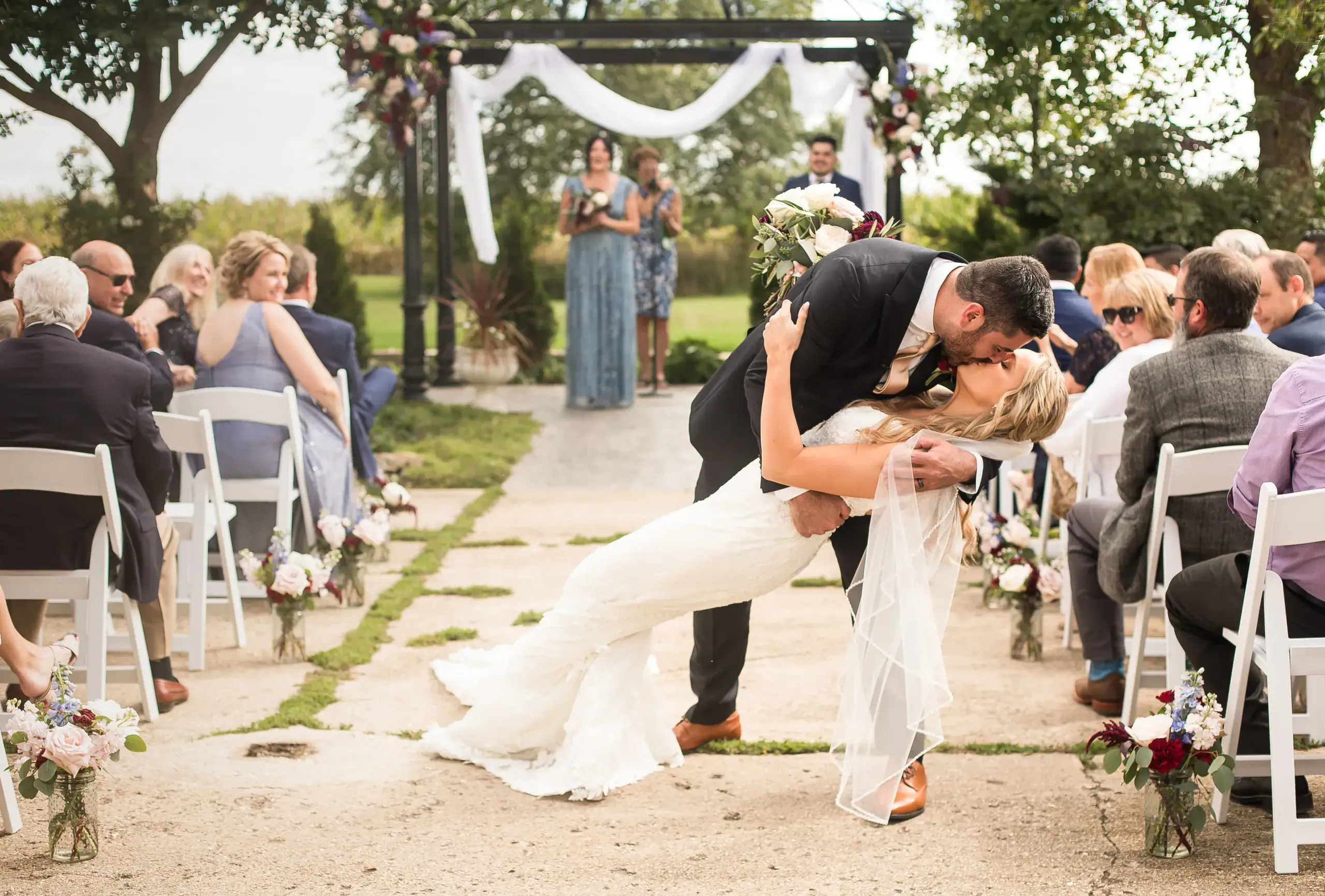 Groom dipping bride and kissing at end of aisle
