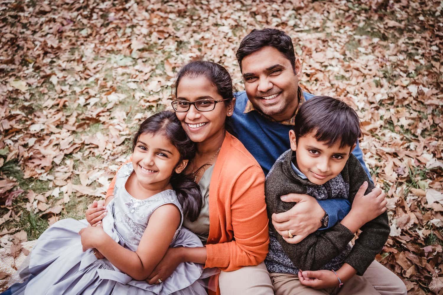 loving family with young children sitting in fall leaves