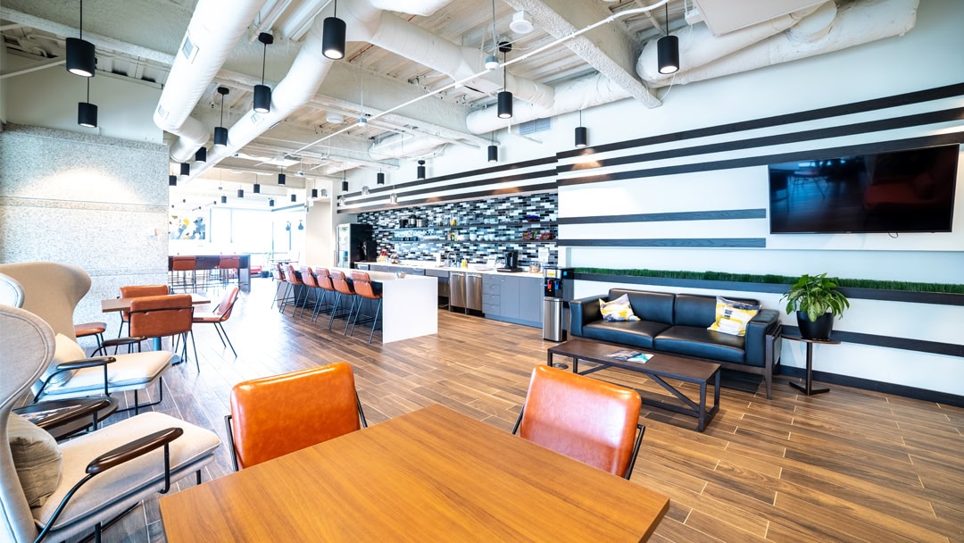 Modern office lounge with stylish seating, a contemporary kitchen area, and inviting workspaces at Office Evolution franchise locations.