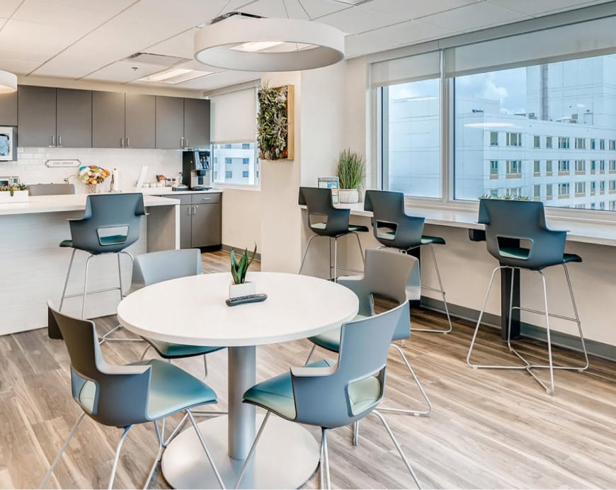 Modern office break area with comfortable seating, natural lighting, and a coffee station, showcasing a professional and inviting environment for Office Evolution franchising.