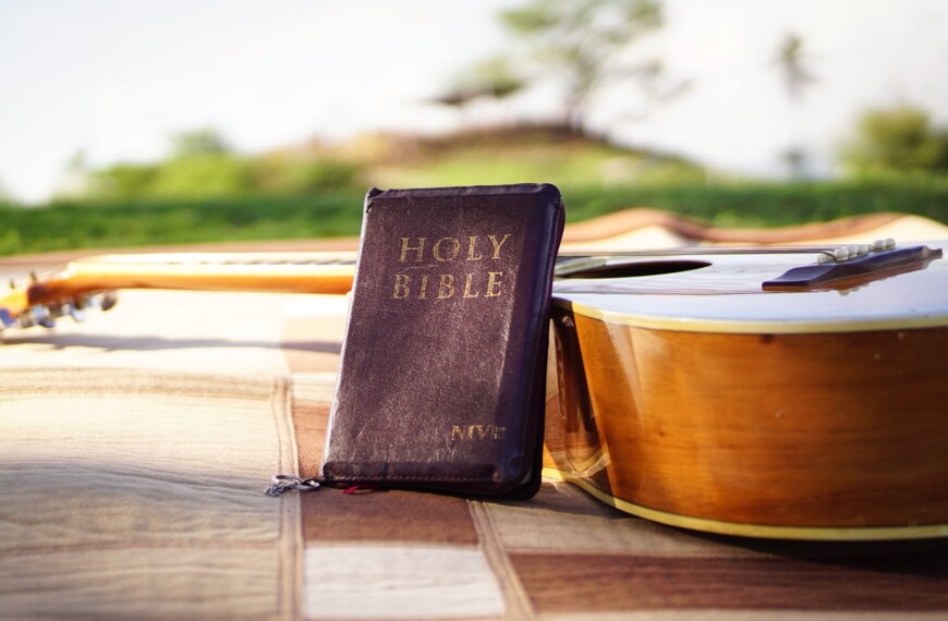 photo of holy bible near acoustic guitar