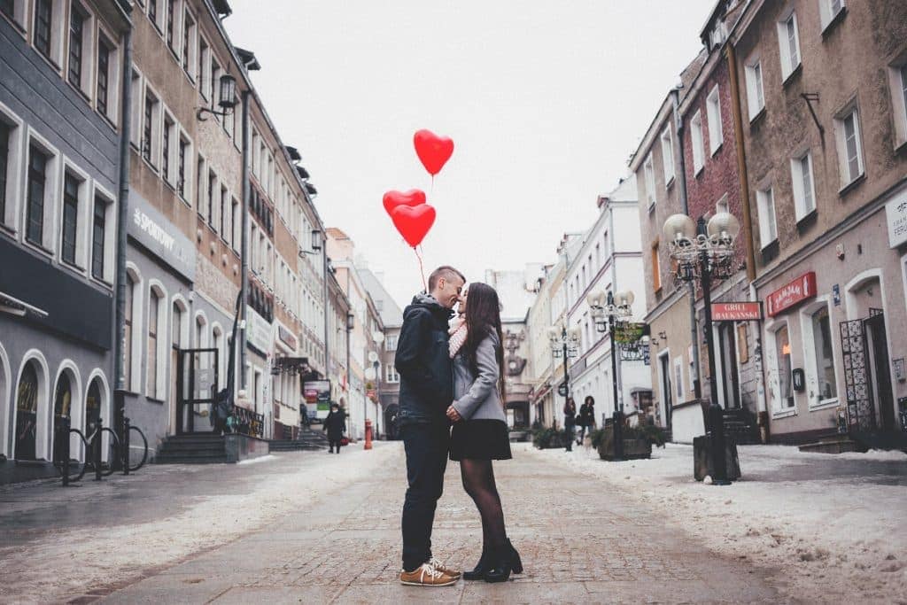 A couple kissing with heart shaped balloons drifting over them