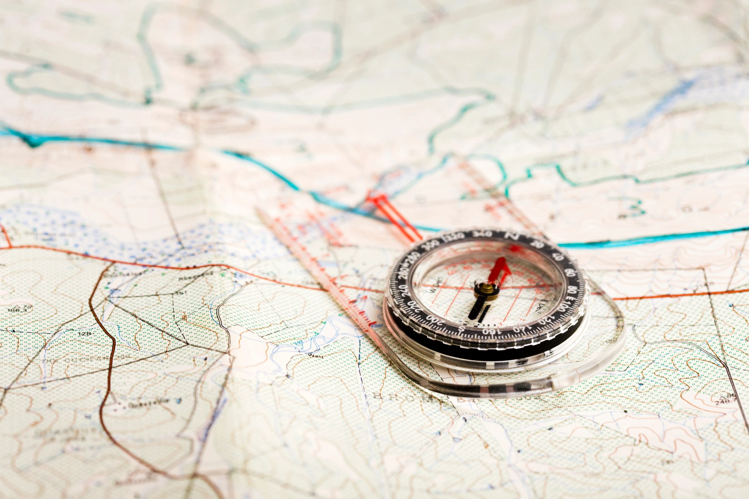 A compass resting on a detailed topographic map, illustrating the route-research approach behind every Global Summit Guide peak guide
