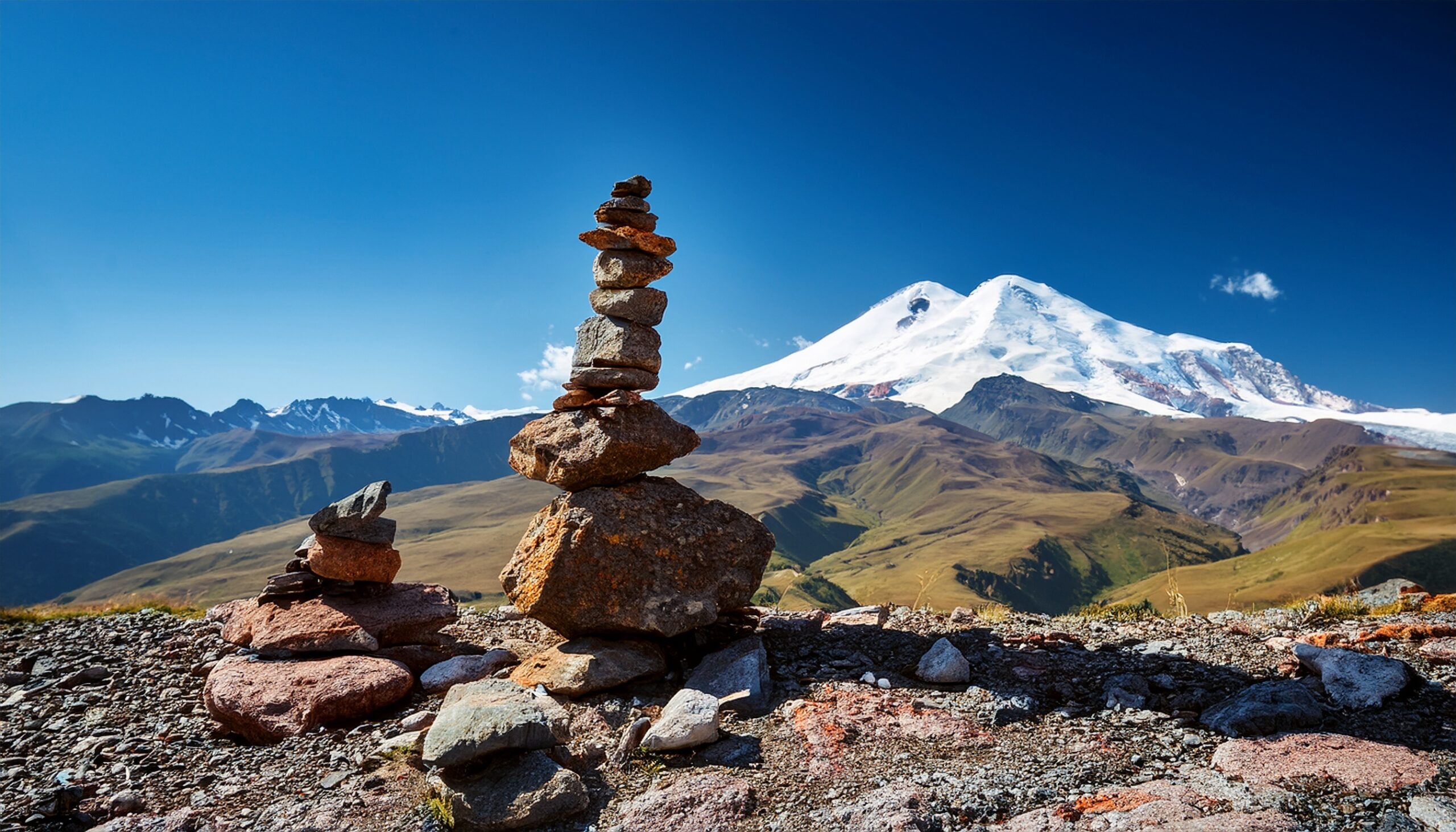 Rock cairns and trail markers in mountain terrain representing the navigation and route finding skills essential for mountain safety including reading topographic maps using a compass for bearings interpreting GPS coordinates following cairns and trail blazes recognizing when trails fade or split avoiding navigation errors that lead to getting lost while hiking and applying the STOP acronym framework which stands for stop moving think calmly observe surroundings and plan deliberately when becoming disoriented in mountain terrain where rescue may be hours or days away making navigation competence one of the foundational pillars of mountain safety alongside the 10 essentials packing framework