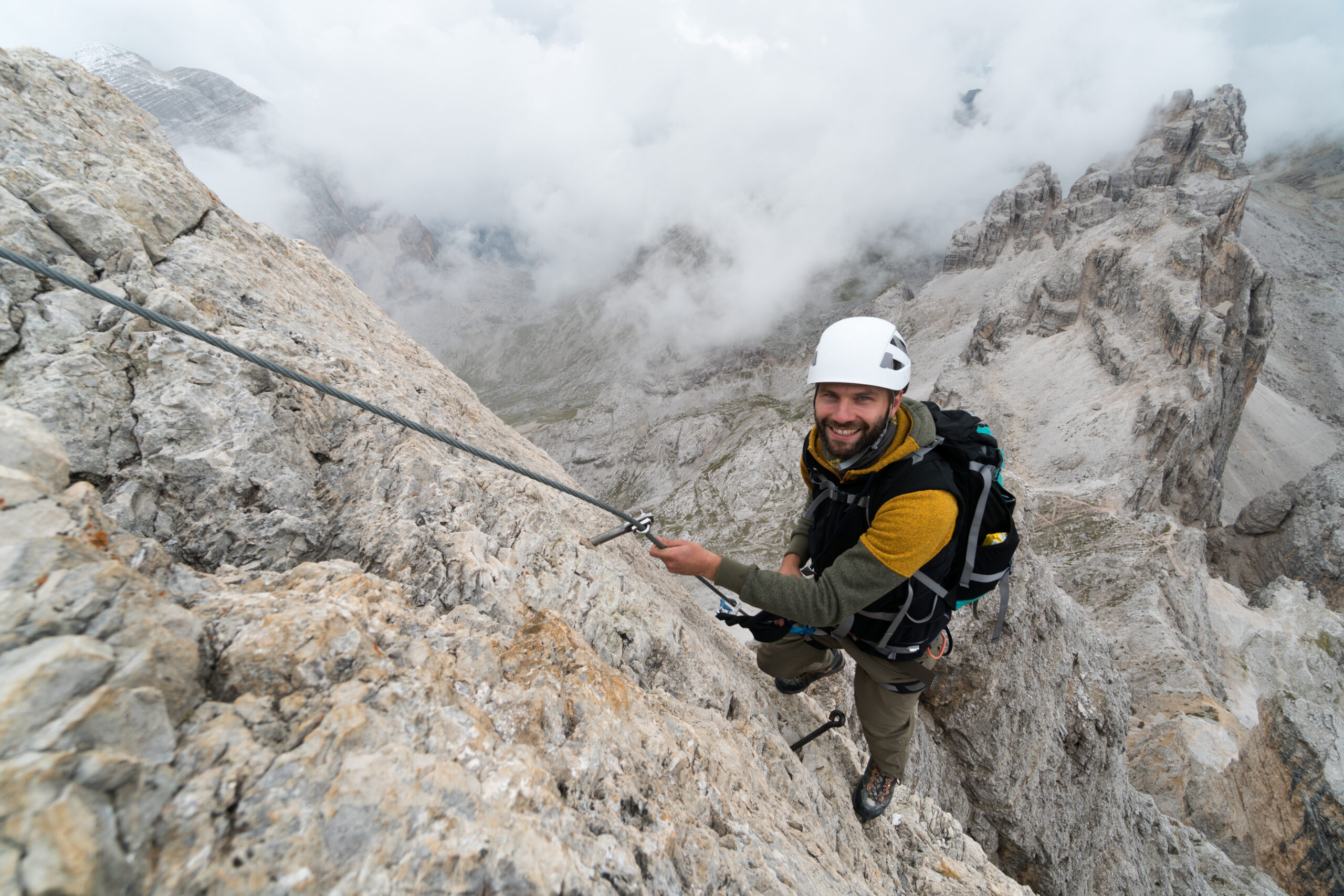 Climber on an exposed rocky mountain face wearing a helmet