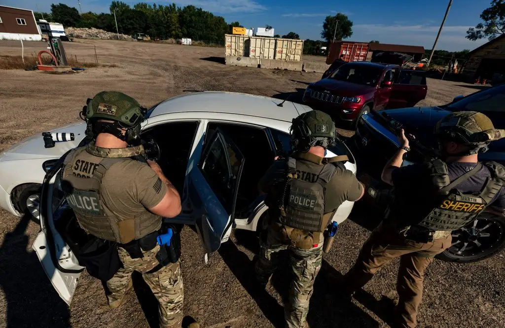 three officers standing outside of compact car during vehicle tactics and suppression course