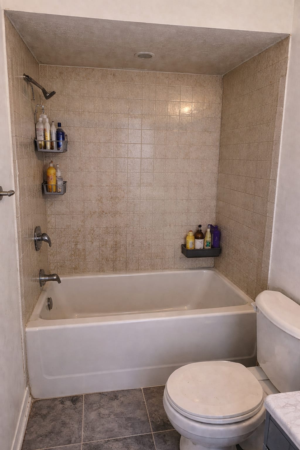 Original bathtub and beige tile surround before the modern walk-in shower conversion.
