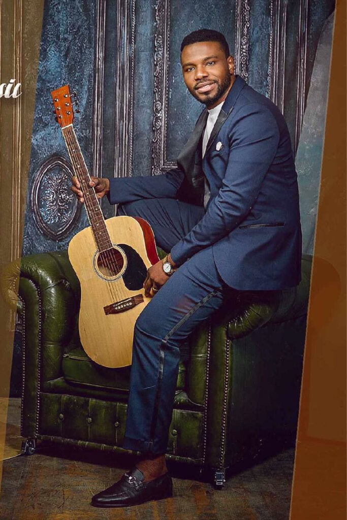 Tom Mulenge, Afro-gospel artist from Bolton, in a Blue textured jacket against a dark backdrop.