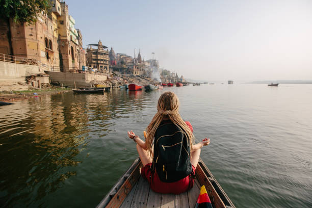 Traveler female wearing dreadlocks seating in wooden boat and enjoy Varanasi view