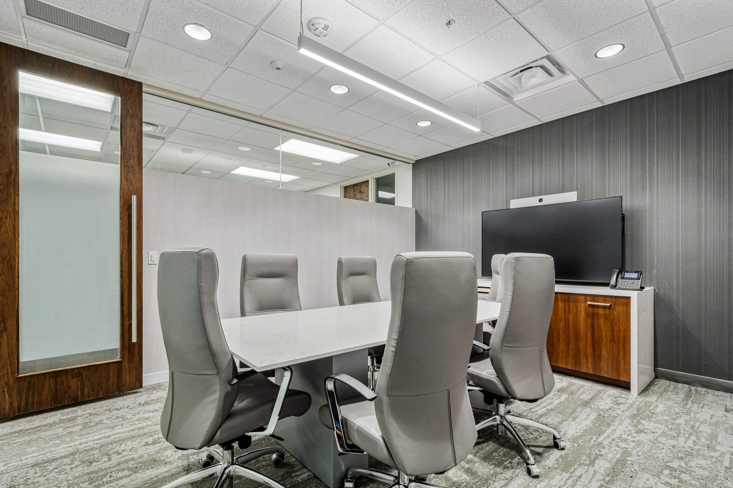 Modern conference room with sleek office chairs, large screen, and professional workspace setup.