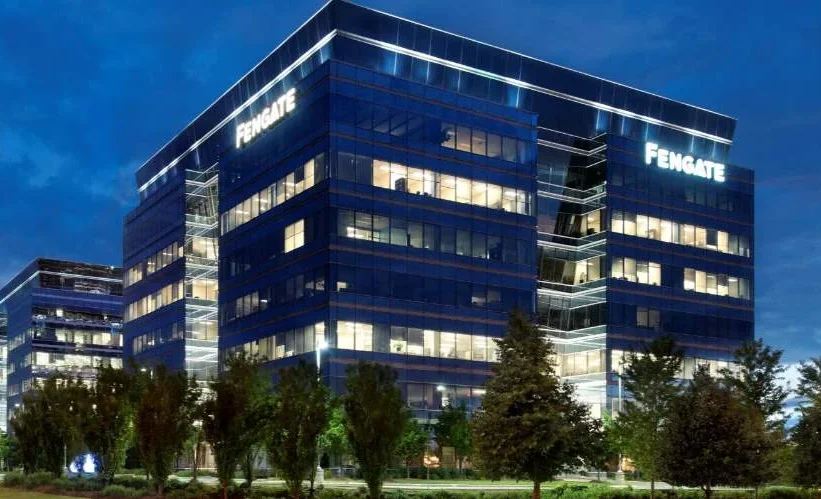 Fengate office building with modern glass facade at night, illuminated and surrounded by trees.