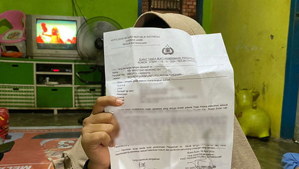 Korban menunjukkan surat laporannya ke polisi, di rumahnya, Sabtu 6 April 2024 | infojambi