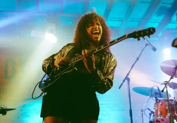 Jackie Venson on stage performing with guitar