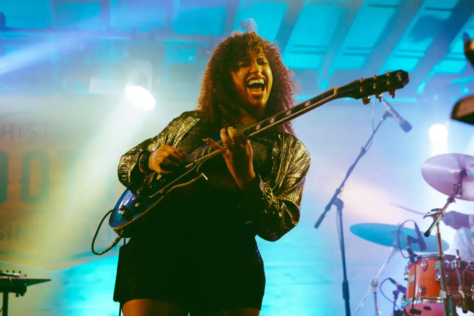Jackie Venson on stage performing with guitar