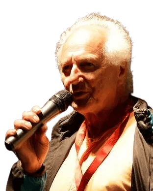 Rico Ferrara wearing a tan shirt and dark jacket speaking into microphone