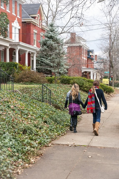 Two people walking together through a Louisville neighborhood