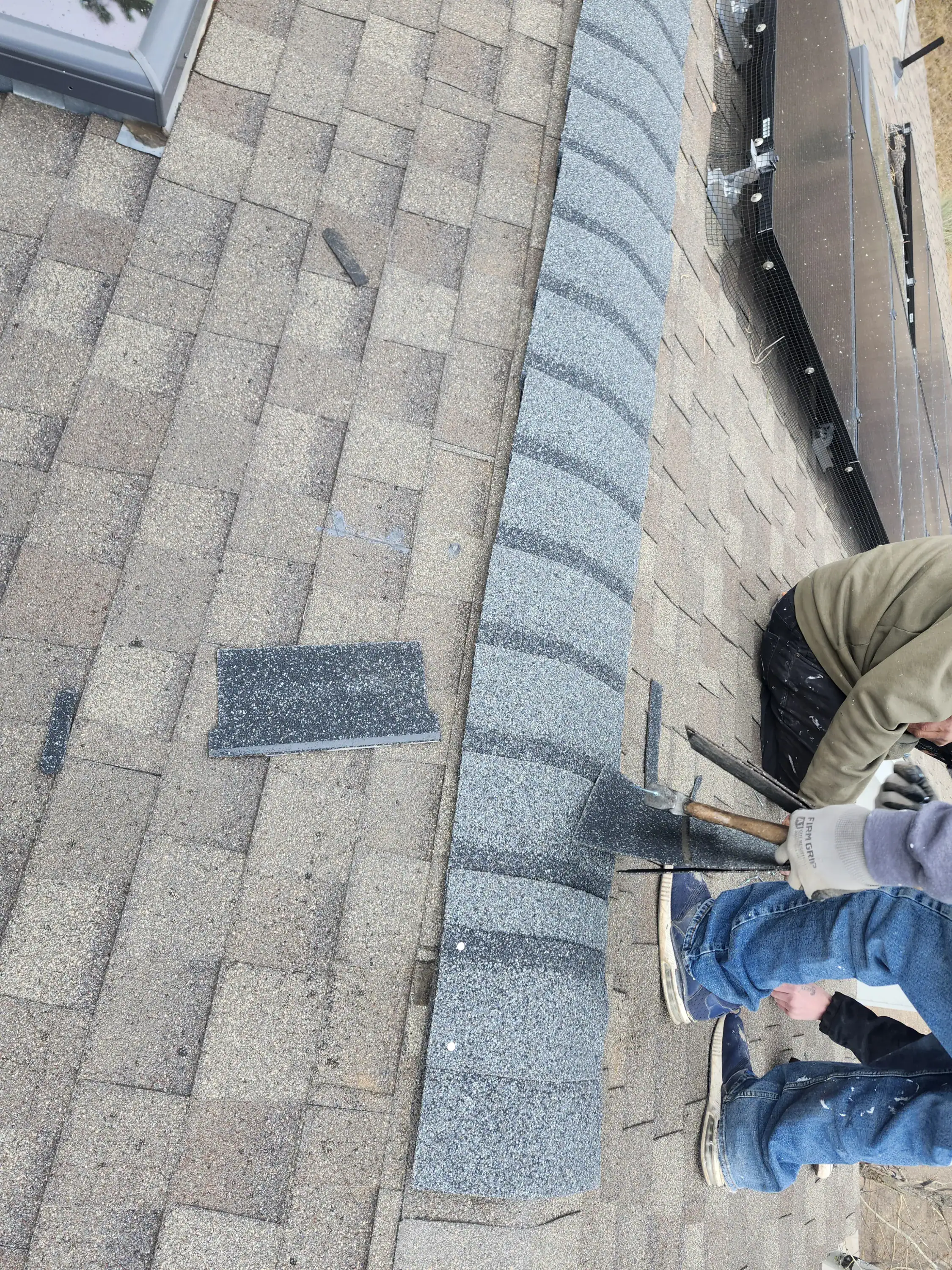 New ridge cap shingles being installed alongside solar panels Left Hand Canyon roof repair Colorado