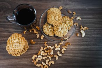 Keto cookies with coffee and cashews arranged on a wooden contai