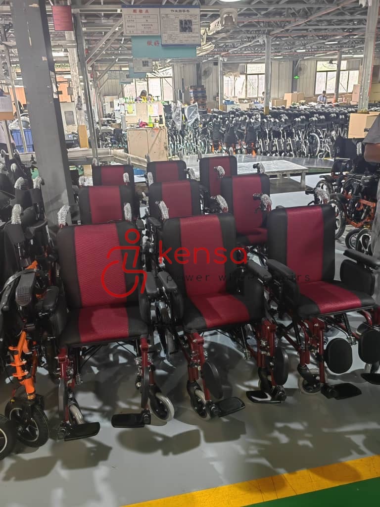 Kırmızı siyah renkli elektrikli tekerlekli sandalyeler üretim veya depolama alanında sıralanmış.