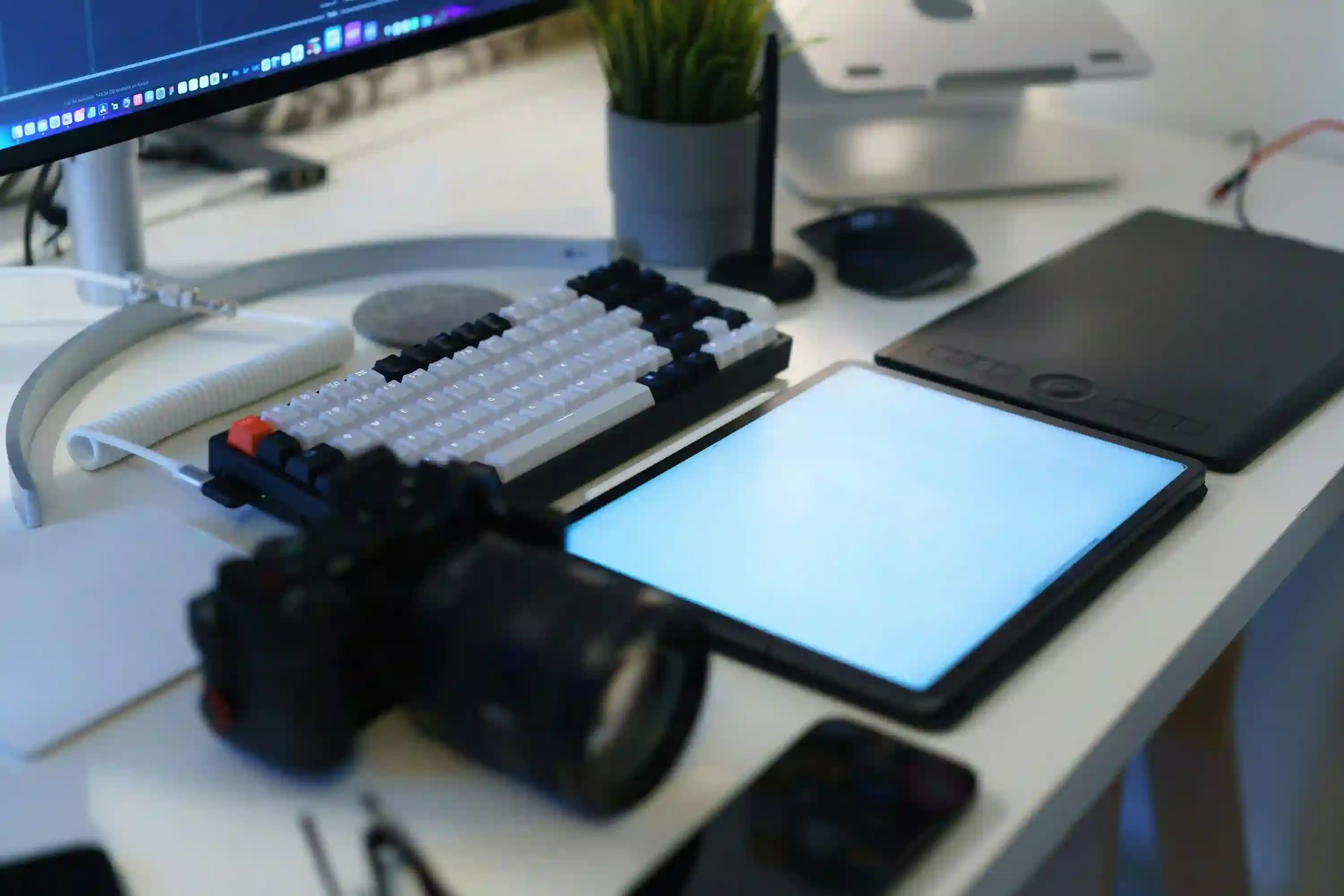 A camera, drawing pad, and keyboard sitting on a desk. This represents my IT and Digital Design service.