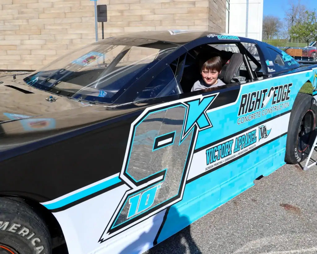 A child smiles from the driver's seat of Adam Casari's race car.
