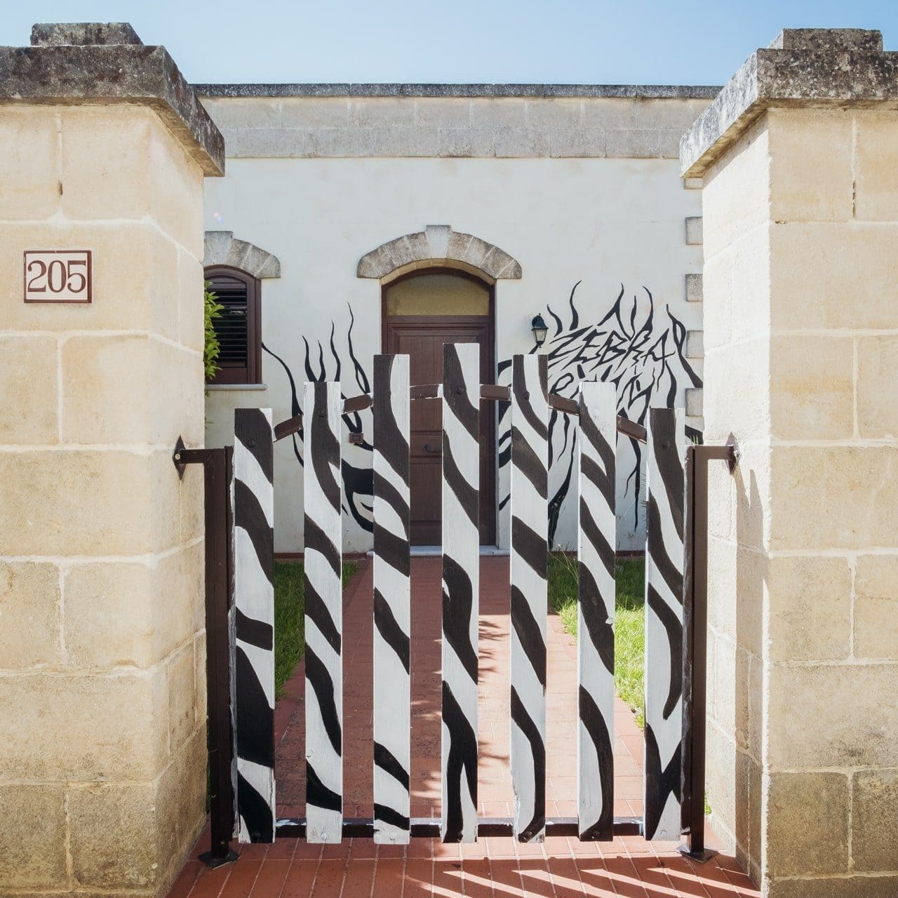esterno camera zebra con cancelletto dipinto e scritta zebra room sulla parete esterna