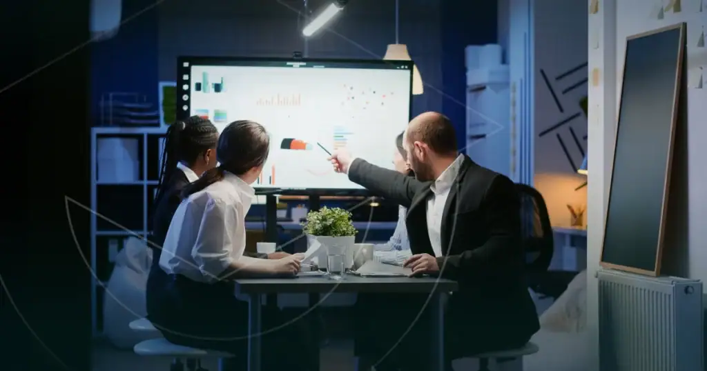 Team analysiert Daten der Lernplattform auf einem grossen Bildschirm im Büro