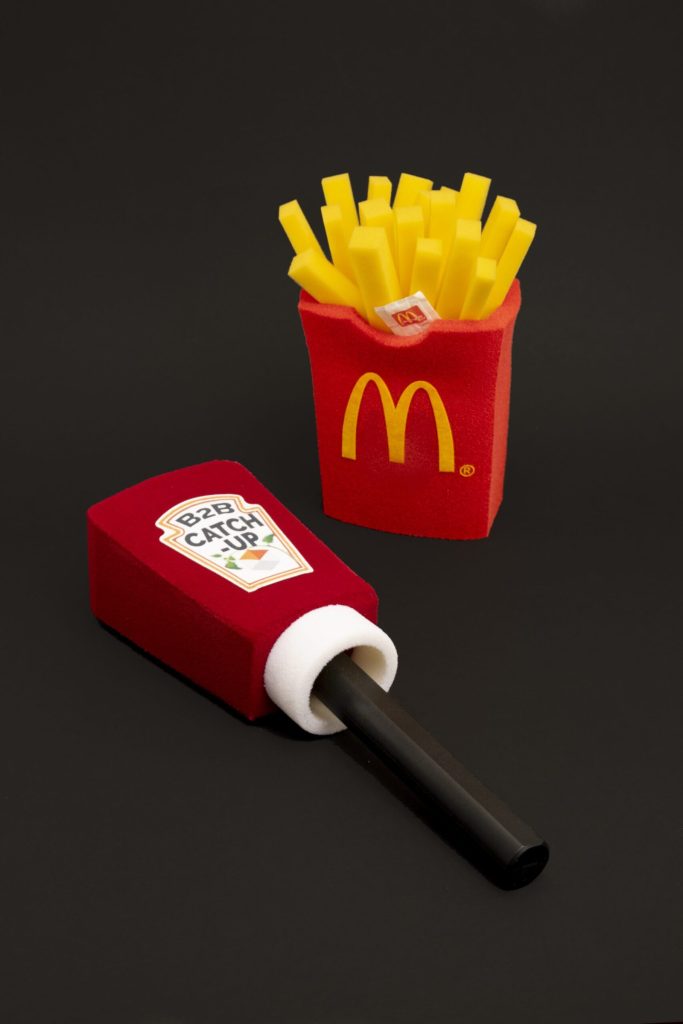 Custom foam microphone windshields in creative shapes, including a fries carton design and a branded handheld mic cover, demonstrating bespoke on-camera branding for broadcast production.