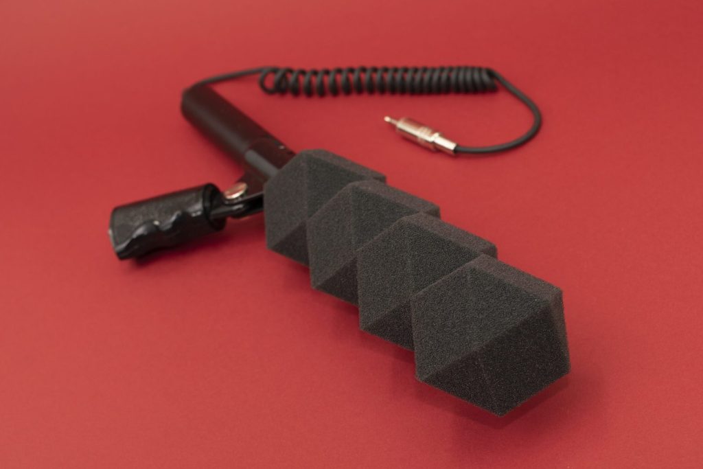 Custom acoustic foam windscreen on a shotgun microphone, shown in a geometric segmented shape for wind noise reduction in broadcast and field recording.