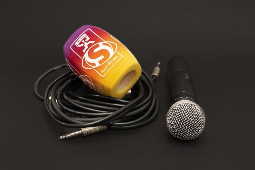 4-sided (square) foam microphone windscreen with a Fosroc logo and “Super6 Rugby” branding in a purple-to-yellow gradient, shown with a handheld microphone and cable on a black background.