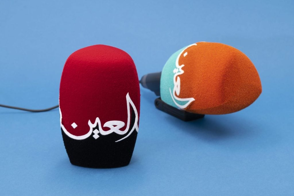 Two custom microphone windshields with Arabic branding, red-black and orange-mint gradient designs, professional broadcast windscreens for Al Aan and Middle Eastern media